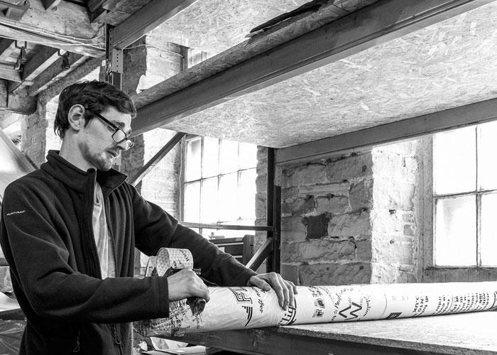 Photo of worker unwrapping campervan insulation roll in a warehouse