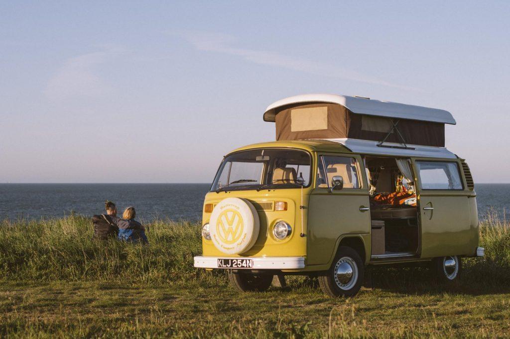 VW campervan with couple looking across the sea